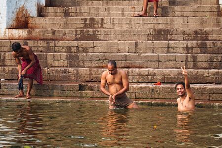 Varanasi, India - Dec 26, 2019: Hindu taking ritual bath in the river Ganga in the holy city of Varanasi, India. The holy ritual bath is held every day.のeditorial素材