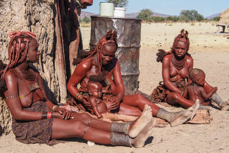 Opuwo, Namibia - Jul 07, 2019: Unidentified Himba women with the typical necklace and hairstyle in...
