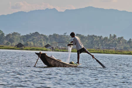 Inle Lake, Myanmar - Nov 08, 2019: Fisherman rowing boat by one leg on Inle Lake, Myanmar. Inle Lake is famous for its floating villages and gardens.のeditorial素材