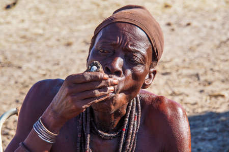 Opuwo, Namibia - Jul 07, 2019: Old Namibian man smoking a cigar, seen in Opuwo, the capital of the Kunene Region in north-western Namibia, Africaのeditorial素材