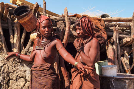 Opuwo, Namibia - Jul 07, 2019: Unidentified Himba women with the typical necklace and hairstyle in...
