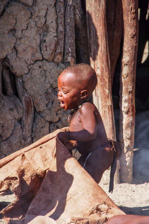 Opuwo, Namibia - Jul 07, 2019: Young unidentified Himba infant in a himba tribe villageのeditorial素材