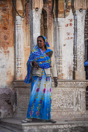 Nawalgarh, India - Dec 28, 2019: Woman dressed in traditional sari standing in front of a haveli of...