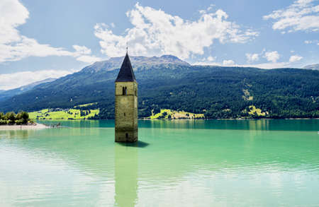 The famous bell tower in the Lake of Reschen - Lago di Resia in South Tyrol, Italy. During WW2 a dam was build and put the village under water, only the tower is still visible now.の写真素材