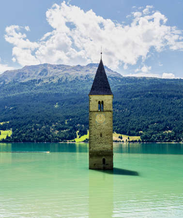 The famous bell tower in the Lake of Reschen - Lago di Resia in South Tyrol, Italy. During WW2 a dam was build and put the village under water, only the tower is still visible now.の写真素材