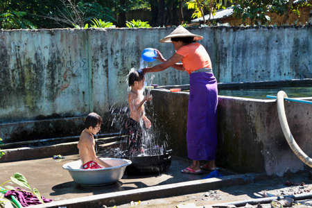 Mandalay, Myanmar - Nov 09, 2019: Burmese mother washing their kids with water in Mandalay, Myanmar, former Burma in Asiaのeditorial素材