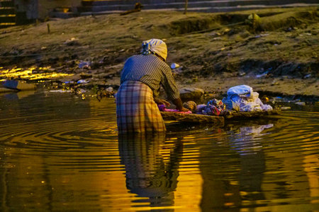 Varanasi, India - Dec 26, 2019: Woman washing clothes at river Ganges in Varanasi, India, Asiaのeditorial素材