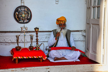 Jodhpur, India - Jan 02, 2020: Portrait of aged Rajasthani man in traditional dress and colorful turban smoking hookah at Mehrangarh Fort in Jodhpur, Indiaのeditorial素材