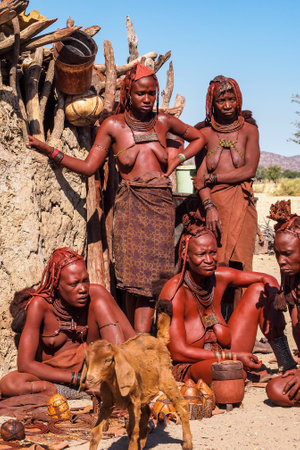 Opuwo, Namibia - Jul 07, 2019: Unidentified Himba women with the typical necklace and hairstyle in himba tribe villageのeditorial素材
