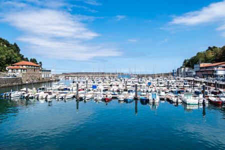 White sail boats in Mutriku port and old town, Basque country, Spain. View of colorful boats docked on Motrico marina facing the Cantabric sea.の写真素材