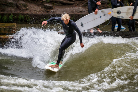 Munich, Germany - Jun 04, 2022: Surfer in the city river, Munich is famous for people surfing in urban enviroment called Eisbachのeditorial素材