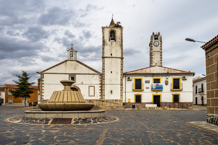 Herreruela, Spain - Mar 01, 2023: Nest of storks on top of old stone bell tower with iron cross at Herreruela, Extremadura in Spain. Paradise for storks.のeditorial素材