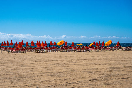 Gran Canaria, Spain - Feb 15, 2023: sandy beach with plastic chairs and umbrellas near Atlantic ocean in Maspalomas, Gran Canaria in Spainのeditorial素材