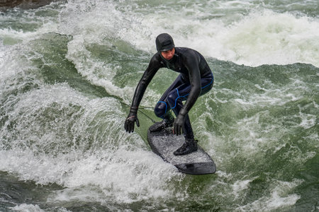 Munich, Germany - October 13, 2023: Surfer in the city river, Munich is famous for people surfing in...