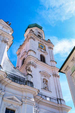 St. Stephan's cathedral in Passau, Germany is an old white church with green metal domes on top of the towers. In front of the church is a statueの写真素材