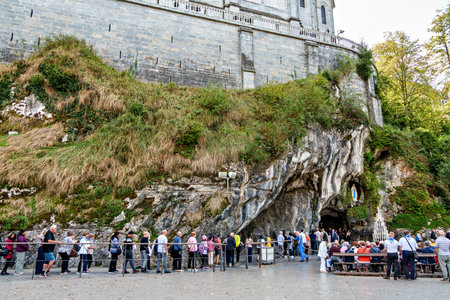 Lourdes, France - Sep 28, 2025: Pilgrims waiting at the grotto of Massabielle, the place where the events of the Lourdes apparitions occurred, located at the Sanctuary of Our Lady of Lourdes in Franceのeditorial素材