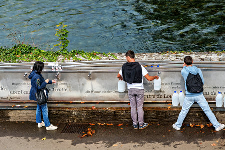 Lourdes, France - Sep 28, 2025: Pilgrims to the Sanctuary of Lourdes in France, Europe filling up bottles with Holy waterのeditorial素材
