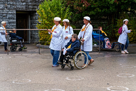Lourdes, France - Sep 30, 2025: Disabled persons in wheelchairs crossing the square of the sanctuary...