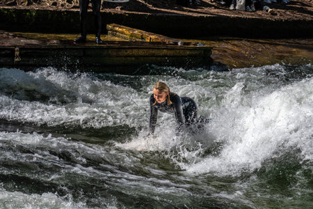 Munich, Germany - Apr 12, 2025: Surfer in the city river, Munich is famous for people surfing in...