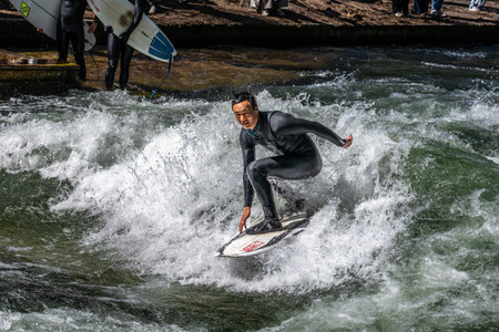 Munich, Germany - Apr 12, 2025: Surfer in the city river, Munich is famous for people surfing in...