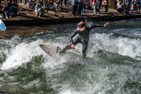 Munich, Germany - Apr 12, 2025: Surfer in the city river, Munich is famous for people surfing in...