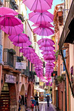 Collioure, France - Nov 03, 2025: Pink umbrellas hanging in the streets of Collioure in France. Village next to Mediterranean sea. Tourism in the south of France, Europeのeditorial素材