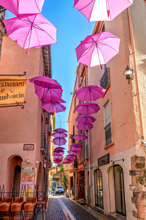 Collioure, France - Nov 03, 2025: Pink umbrellas hanging in the streets of Collioure in France. Village next to Mediterranean sea. Tourism in the south of France, Europeのeditorial素材