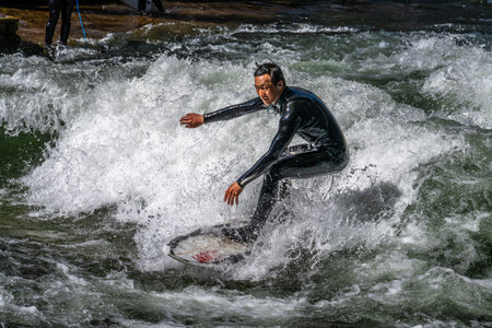 Munich, Germany - Apr 12, 2025: Surfer in the city river, Munich is famous for people surfing in...