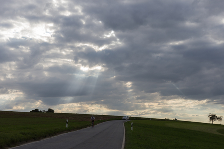 on a very sunny day in august in south germany you see road  beside green fields with contrastful cloudy skyの写真素材