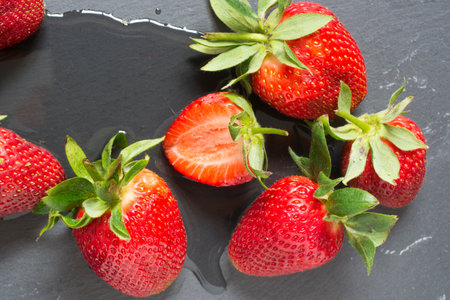 Fresh Strawberries on black slate background, top view, close up, with water, natural lightの写真素材