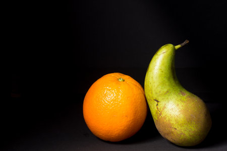 Still life of An Orange and a Pear, fine art image with black background