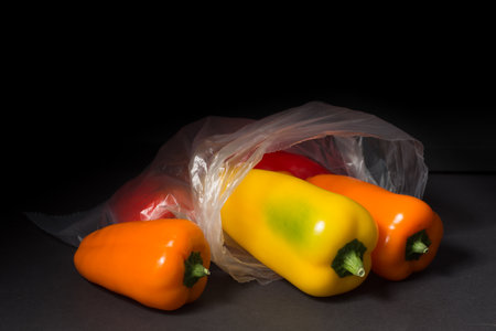 Peppers in a plastic bag on a black background. Copy space.の写真素材