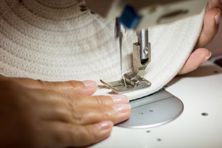 Close-up of a woman's hands sewing on a sewing machine with moving needle. handmade rope craftsの写真素材