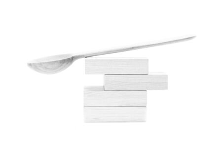 Wooden spoon balancing on wooden cubes in high key on white backgroundの写真素材