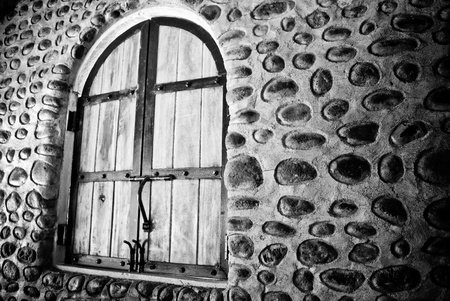A haunting black and white photo of an old rustic stone wall and vintage farm-style arched windows. の写真素材