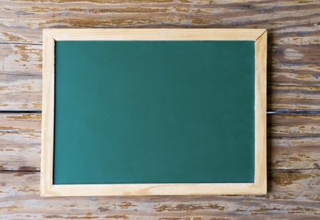 Green blackboard on a background of old, weathered wood.の写真素材
