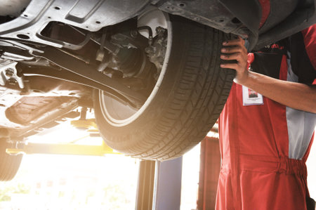 Professional mechanic near wheel center, wheel alignment, mounted on each tire for driving center. Wheel alignment in the garageのeditorial素材
