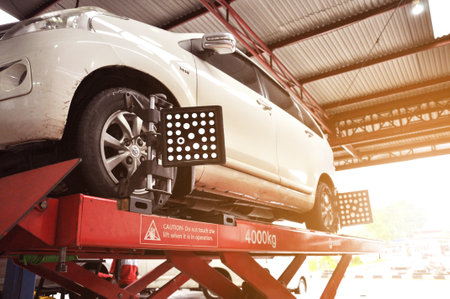 A Car on the Car Steering Wheel Balancer and Calibrate with laser reflector attach on each tire to center driving adjust in the garageのeditorial素材