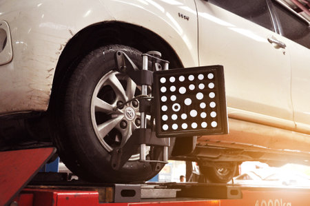 Professional mechanic near wheel center, wheel alignment, mounted on each tire for driving center. Wheel alignment in the garageのeditorial素材