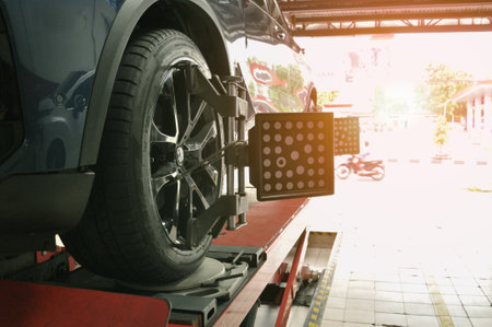 A Car on the Car Steering Wheel Balancer and Calibrate with laser reflector attach on each tire to center driving adjust in the garageのeditorial素材
