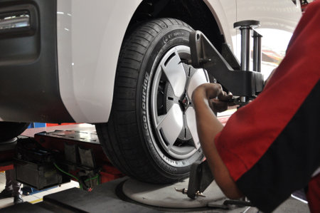 Professional mechanic near wheel center, wheel alignment, mounted on each tire for driving center. Wheel alignment in the garageのeditorial素材