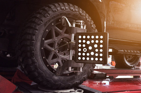 Car wheel alignment calibrate with laser reflector attach on each tire to center driving adjust. Car in auto service. Balancing tire wheel machine.のeditorial素材