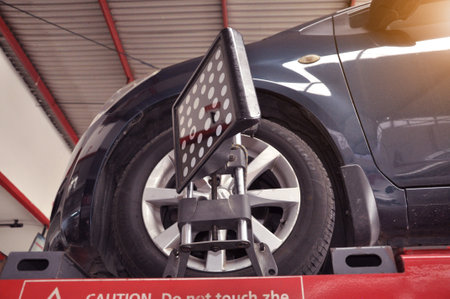 Car wheel alignment calibrate with laser reflector attach on each tire to center driving adjust. Car in auto service. Balancing tire wheel machine.のeditorial素材