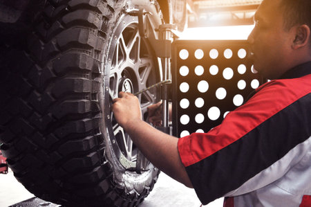 Car wheel alignment calibrate with laser reflector attach on each tire to center driving adjust. Car in auto service. Balancing tire wheel machine.のeditorial素材