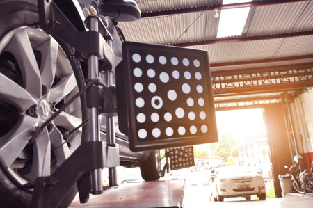 Car wheel alignment calibrate with laser reflector attach on each tire to center driving adjust. Car in auto service. Balancing tire wheel machine.のeditorial素材