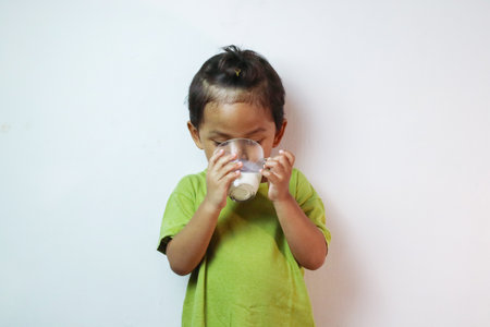 Portrait of asian boy drinking milk and posing on white backgroundの写真素材