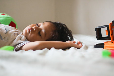 Asian boy wearing pajama sleeping on a bed in a bedroom.の写真素材