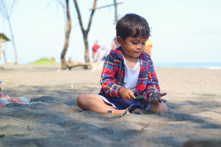 Happy kids have fun on black sand beach. Children sit in seashore. Travel lifestyle, swimming...