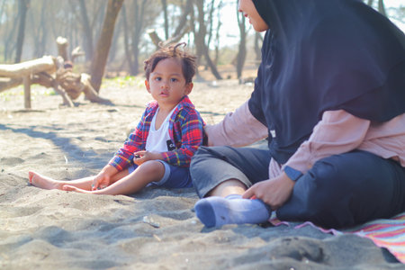 Happy baby boy and mother play sand and toy together on the beach.の写真素材
