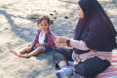 Happy baby boy and mother play sand and toy together on the beach.の写真素材